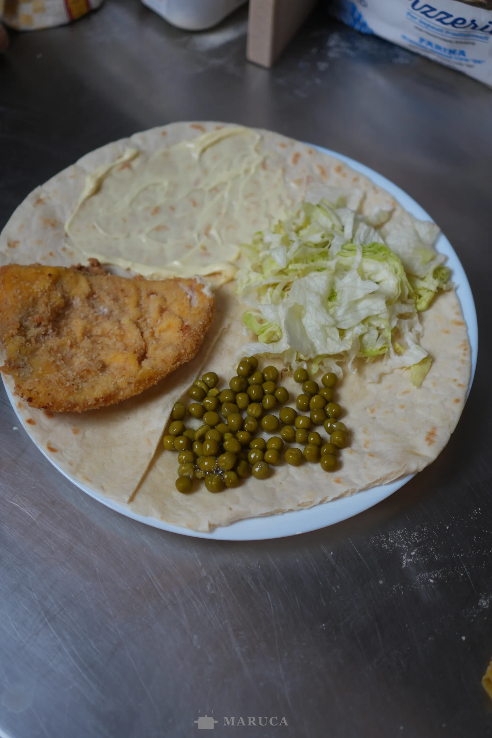 wrap dividido en cuatro con pescado frito, mayonesa, lechuga y arvejas