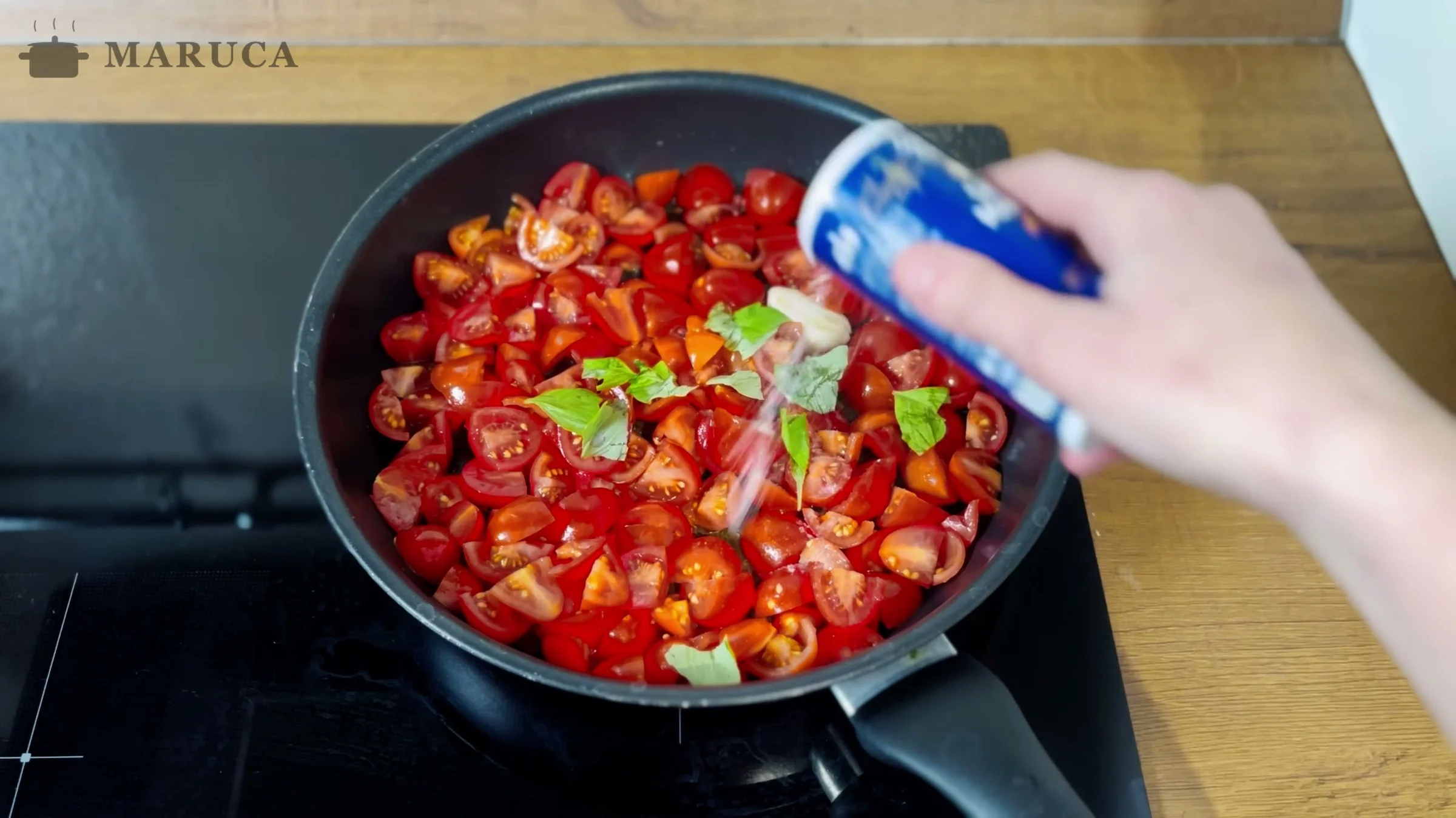 Tomates cherry con albahaca salteándose en la sartén