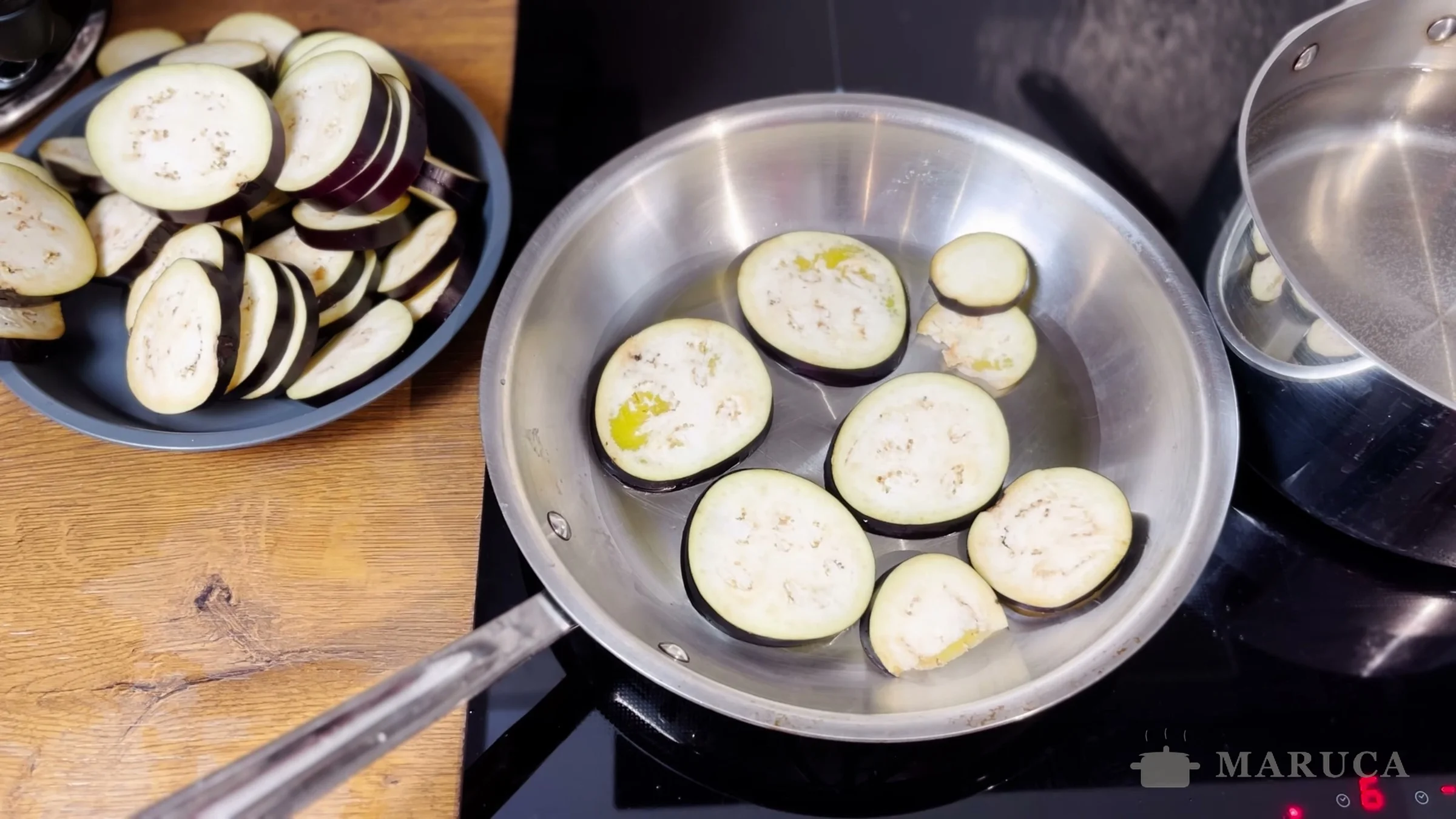 Rodajas de berenjena dorándose en una sartén de acero