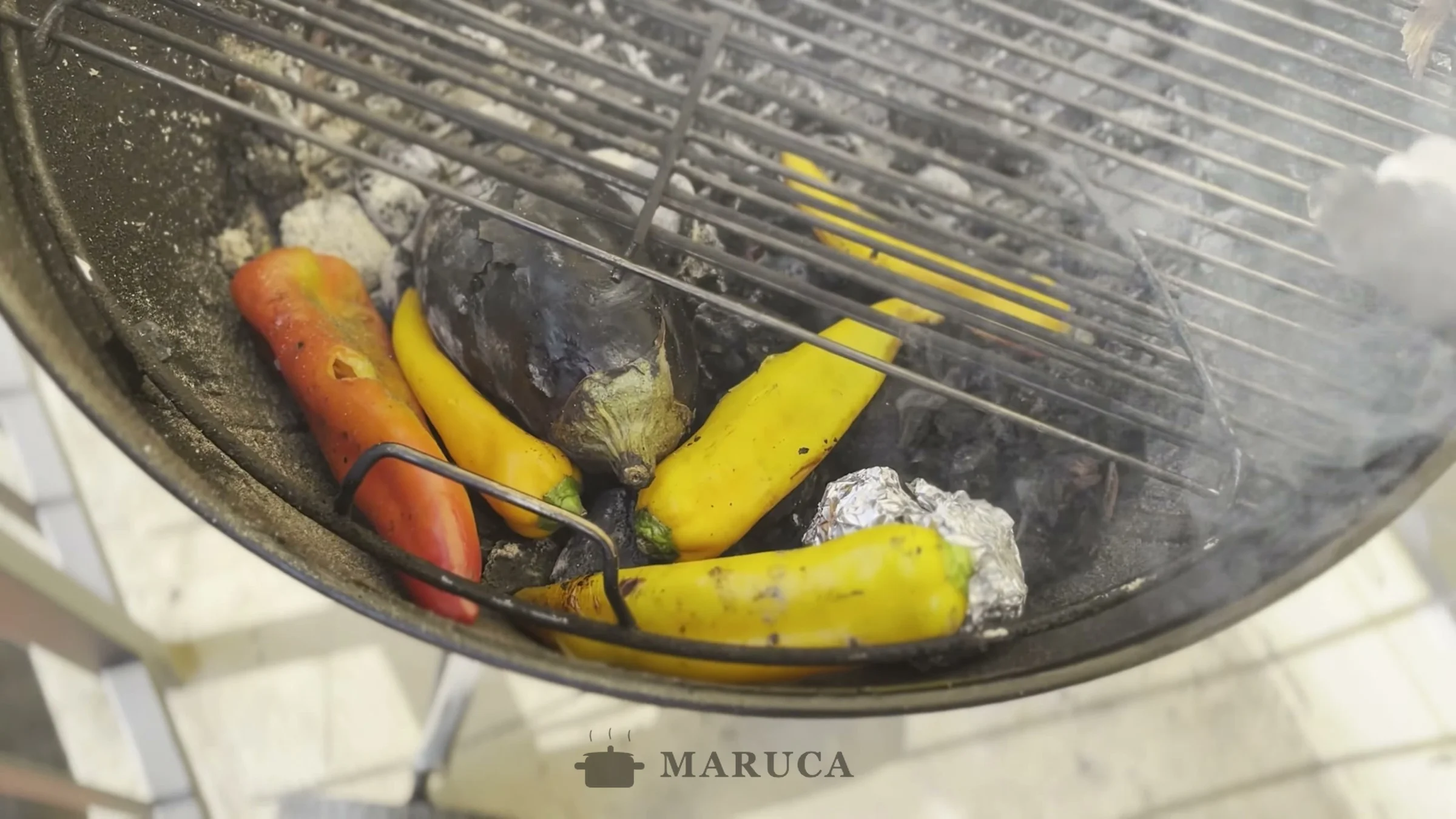 Pimientos, berenjenas y ajo en aluminio asándose en la parrilla