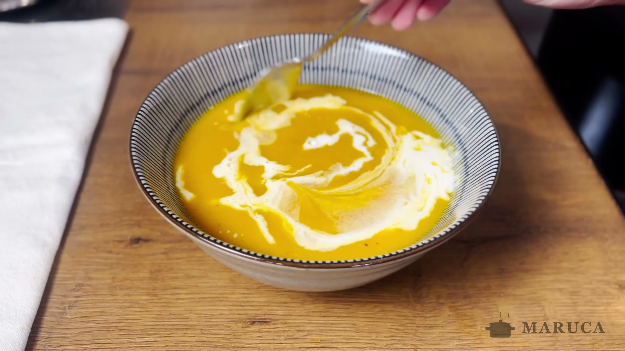 Bowl de sopa de zapallo con crema sobre la mesa de madera