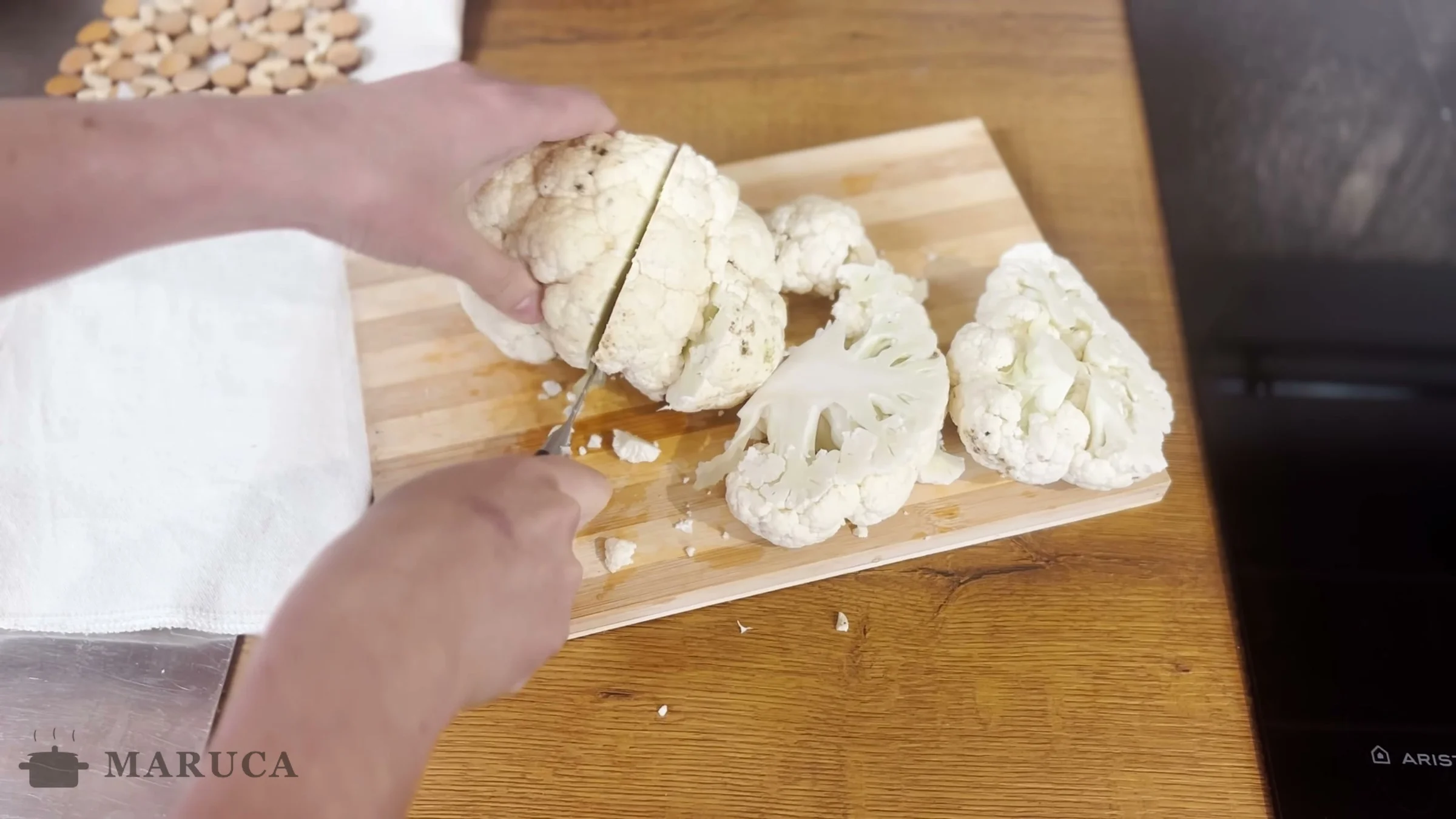 Cortando un coliflor en trozos grandes sobre la tabla de madera
