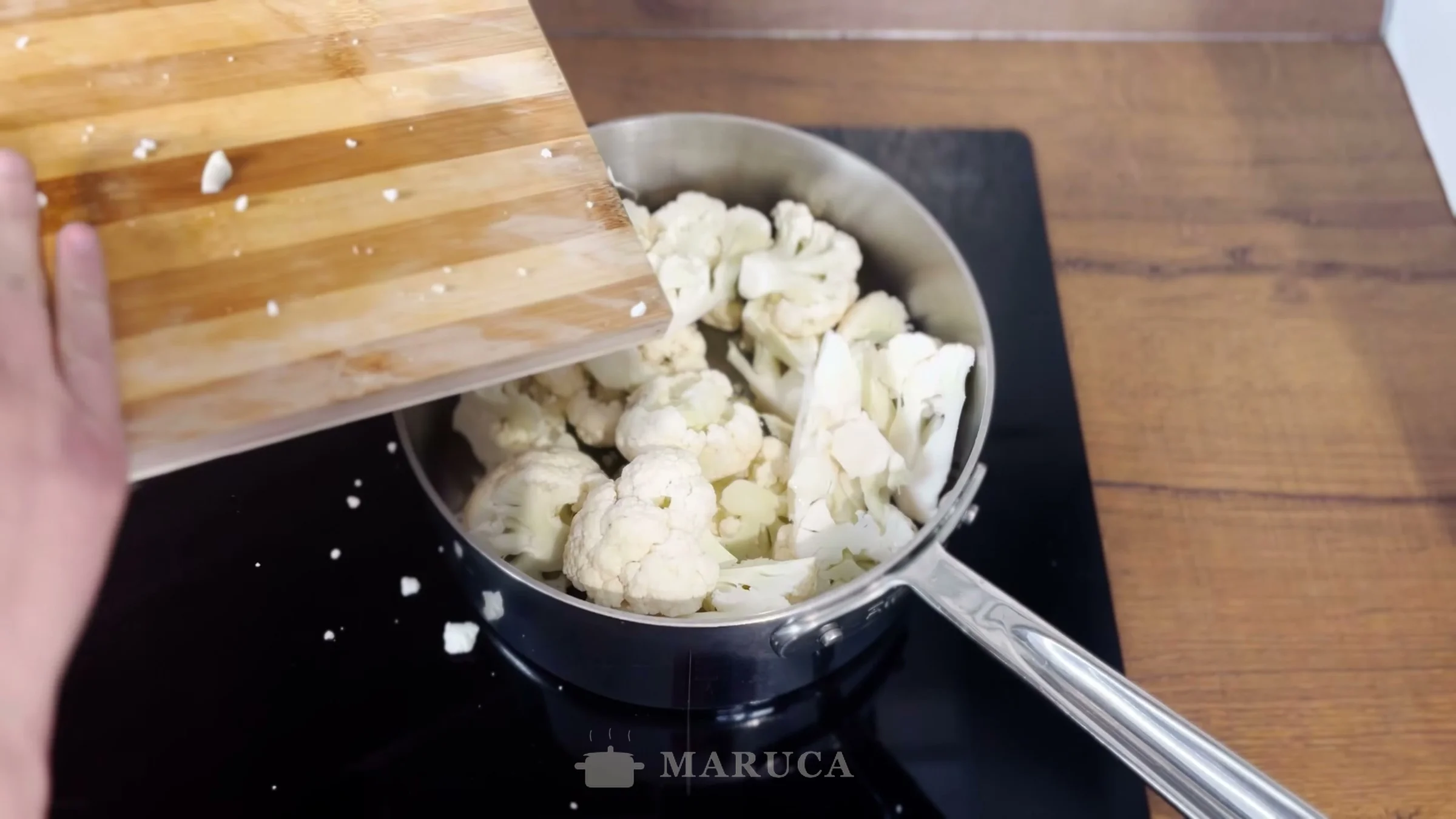 Volcando los trozos de coliflor en la cacerola con el ajo