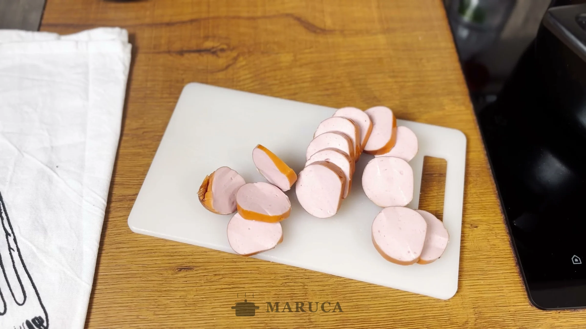Salchicha alemana cortada en rodajas sobre una tabla blanca