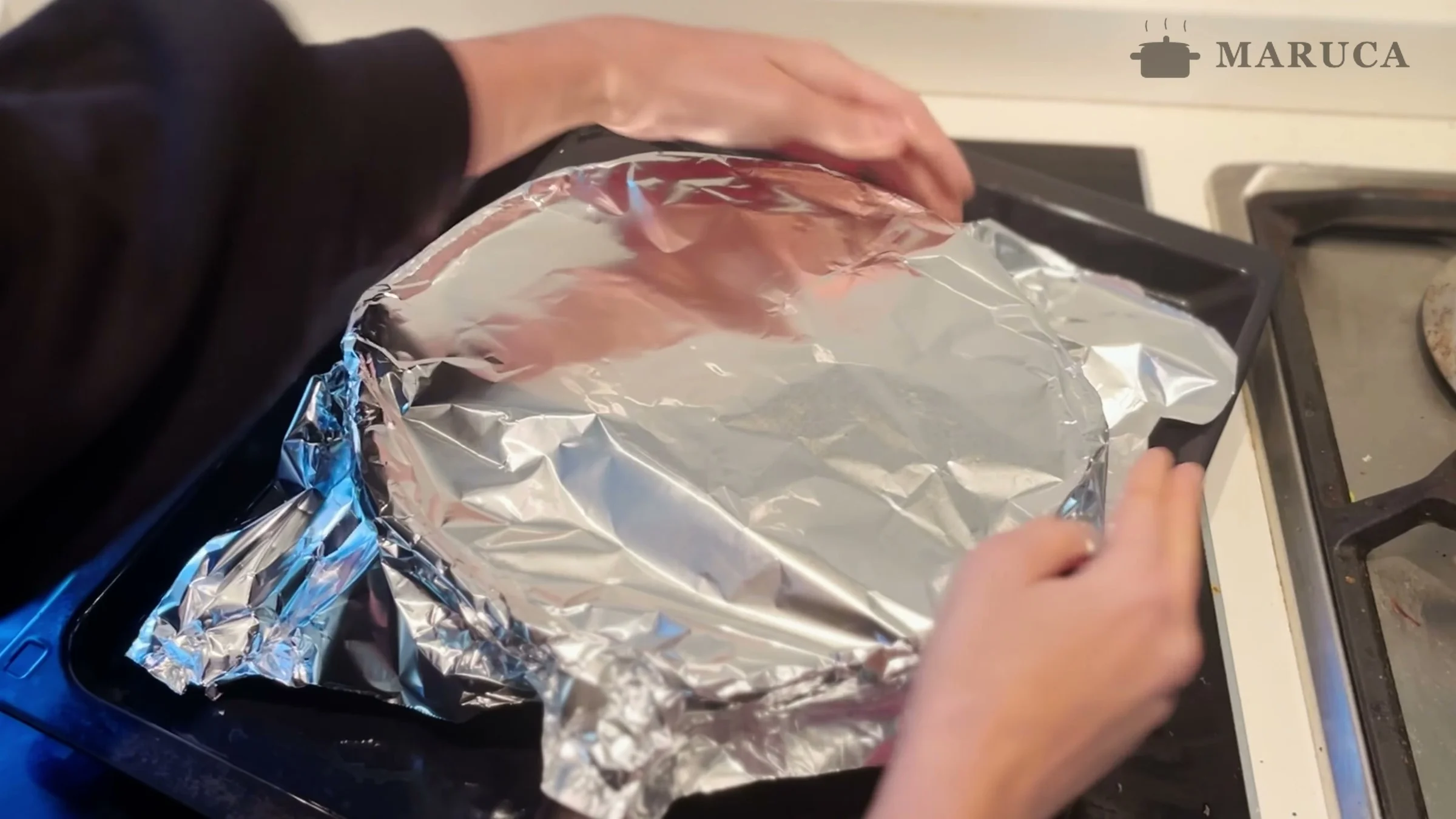 Sartén de osobuco tapada con papel aluminio sobre una asadera lista para el horno