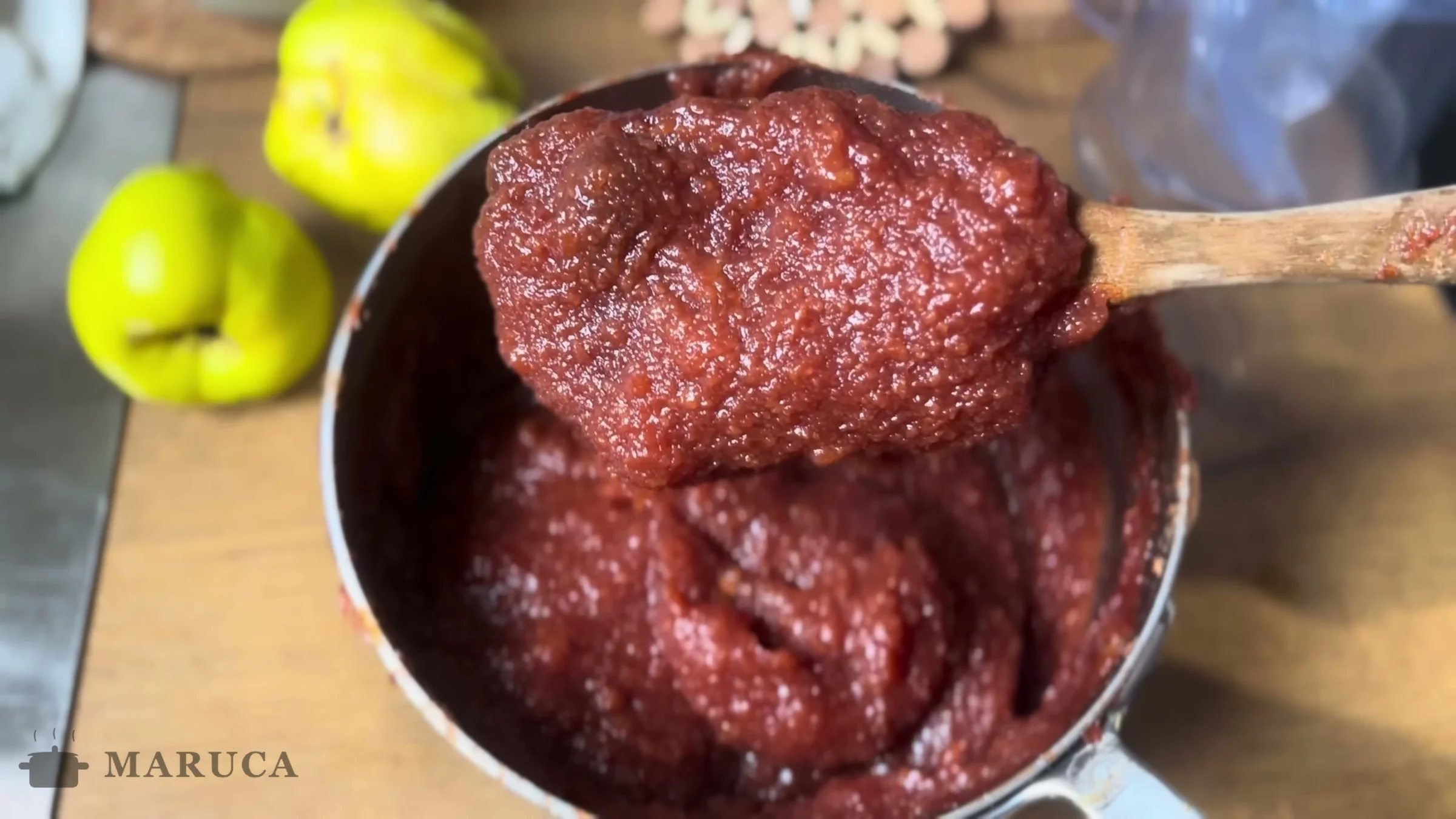 Dulce de membrillo espeso levantado con cuchara de madera, listo para guardar